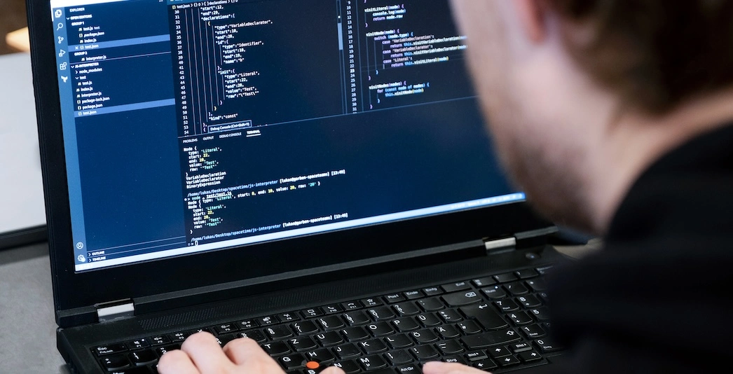 Ein Software-Entwickler sitzt vor einem Laptop und schreibt Code.